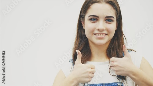 Lovely girl looking at the camera and pointing with at something behind her, then giving thumb up. Wavy hair woman, expressive facial expressions photo