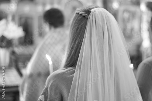 Bride with a candle in the church, the wedding ceremony in the church. Rear view. Black and white photo.