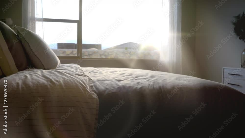 Bed Detail with Sun Flare Move Right. view moves right on a detail shot of a bed in a bedroom with sun flare gleaming through the window Bed Detail with Sun Flare Move Right. view moves right on a detail shot of a bed in a bedroom with sun flare gleaming through the window