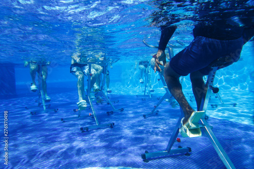 Touristen doing aqua aerobics on exercise bikes in swimming pool tropical hotel