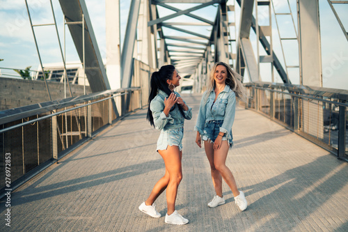 Happy best friends or sisters in jeans wear posing and showing lovely relationship. They look happy