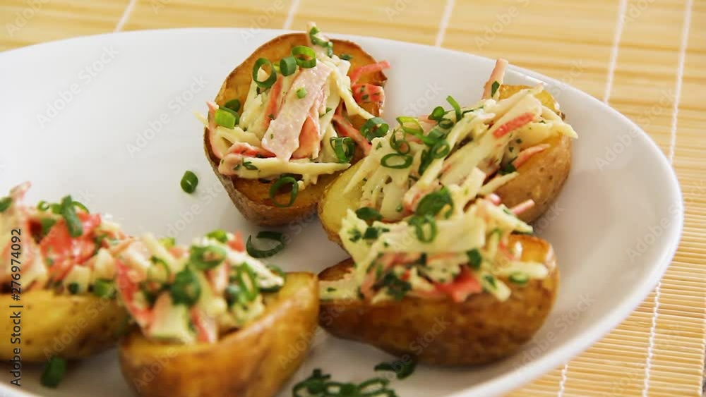 Plate full of rich baked potato halves with shrimp and cheese and hand taking one piece Plate full of rich baked potato halves with shrimp and cheese and hand taking one piece