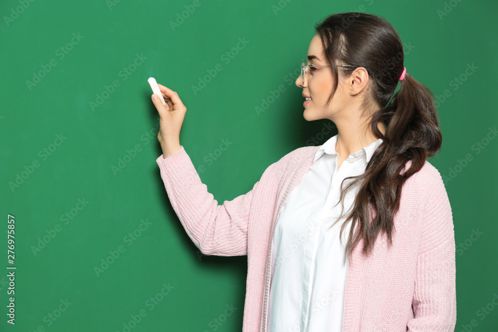 Portrait of beautiful young teacher writing on chalkboard
