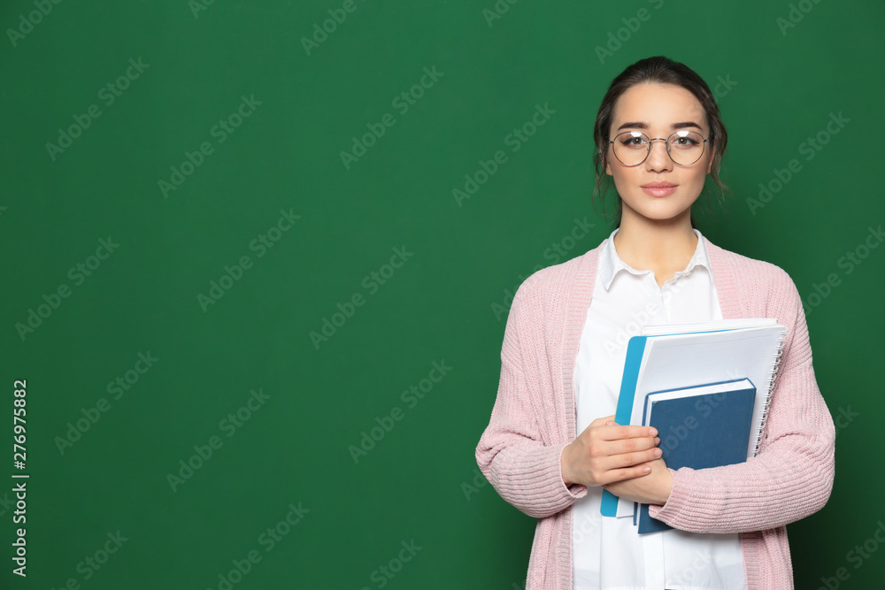 Portrait of beautiful young teacher with books near chalkboard, space for text Portrait of beautiful young teacher with books near chalkboard, space for text