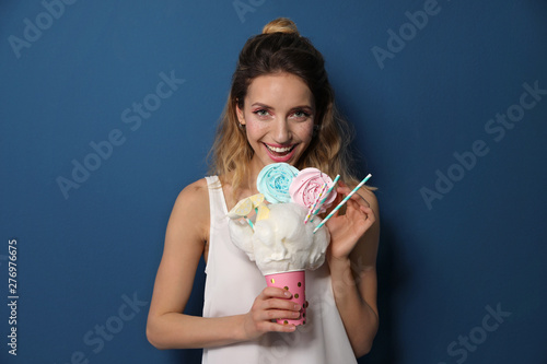 Portrait of young woman holding cotton candy dessert on blue background
