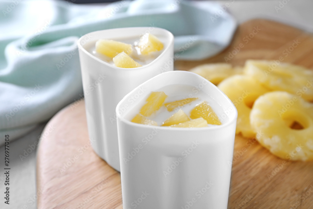 Cups of yogurt with pineapple slices on board, closeup. Multi cooker recipe