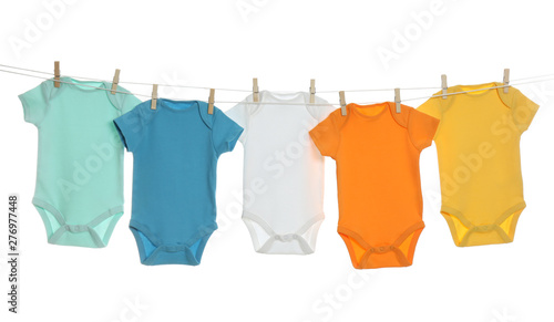 Colorful baby onesies hanging on clothes line against white background. Laundry day