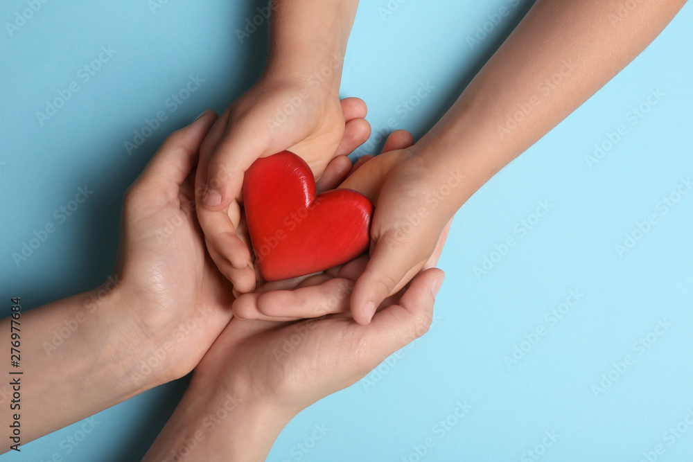 Woman and child holding heart on blue background, top view with space for text. Donation concept Woman and child holding heart on blue background, top view with space for text. Donation concept