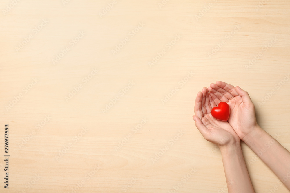 Woman holding heart on wooden background, top view with space for text. Donation concept Woman holding heart on wooden background, top view with space for text. Donation concept