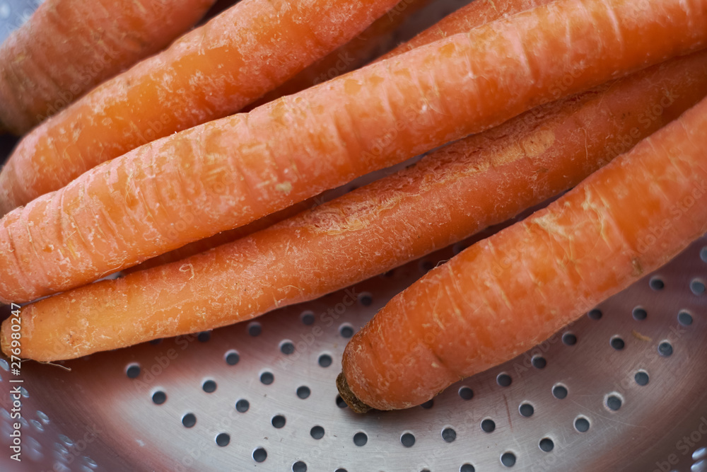 organic orange carrots sit in a draining pan organic orange carrots sit in a draining pan