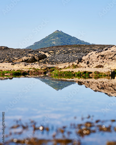 Mountain reflection on the water pond between the rocks at the beach