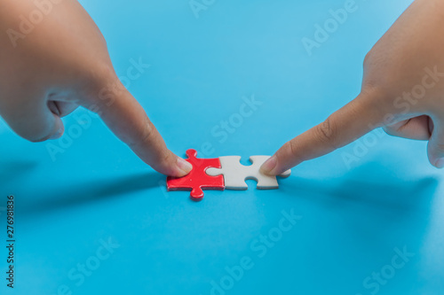 Both hands try to connect the puzzle pieces together 