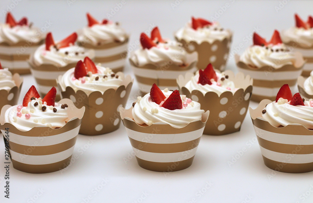 Close-up cupcakes with whipped eggs cream decorated fresh strawberry and chocolate balls on white background. Isolate Close-up cupcakes with whipped eggs cream decorated fresh strawberry and chocolate balls on white background. Isolate