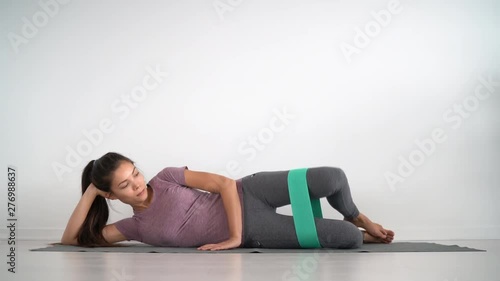 Resistance band clamshell leg workout hip abduction wide loop resistance booty circle bands toning inner and outer thighs, hamstring muscles. Asian fit girl training at home.