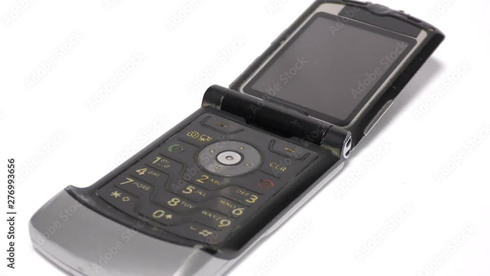 An old mobile phone with flip pad on white surface An old mobile phone with flip pad on white surface