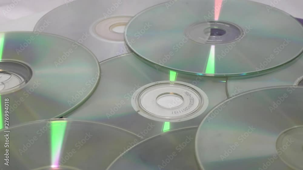 Old cds and dvds moving in circular motion on white surface Old cds and dvds moving in circular motion on white surface