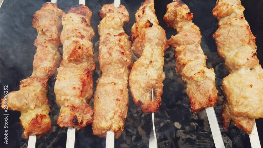 Shashlik preparing on a barbecue grill over charcoal. Grilled kebab cooking on metal skewers Shashlik or Shish kebab popular in Eastern Europe. Shashlik preparing on a barbecue grill over charcoal. Grilled kebab cooking on metal skewers Shashlik or Shish kebab popular in Eastern Europe.