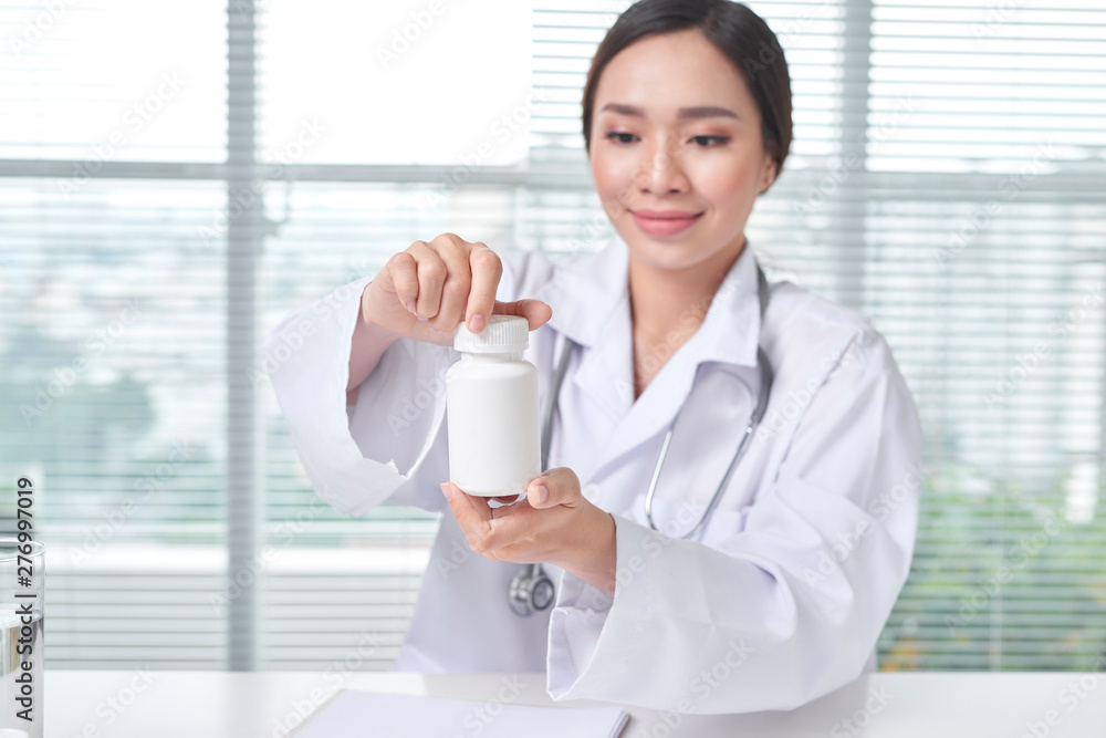 Female doctor holding a box of pills in medical office Female doctor holding a box of pills in medical office