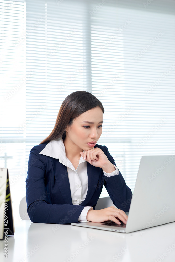 Cheerful employee is holding glasses and looking at screen of laptop with bright smile Cheerful employee is holding glasses and looking at screen of laptop with bright smile