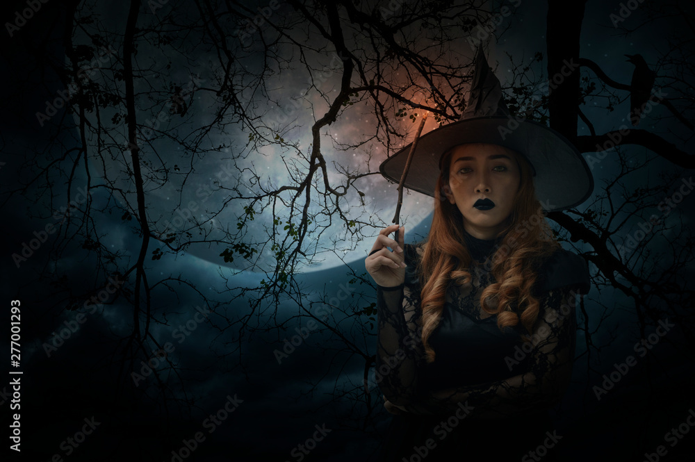 Halloween witch holding magic wand standing over dead tree, full moon, bird and spooky cloudy sky, Halloween mystery concept Halloween witch holding magic wand standing over dead tree, full moon, bird and spooky cloudy sky, Halloween mystery concept