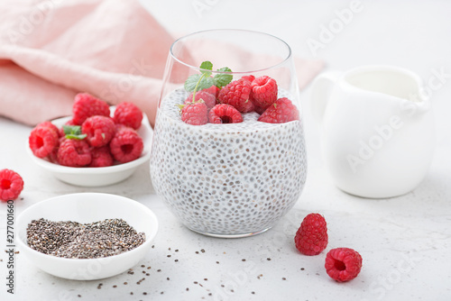 Healthy vanilla chia pudding in a glass with fresh raspberries .