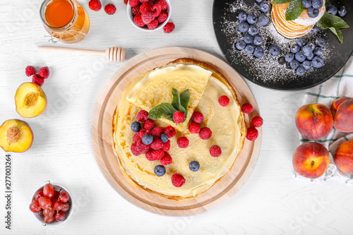 Top view of appetizing pancakes with honey, raspberries and blueberries on a wooden background. Beautiful American pancakes. Maslenitsa. russian pancake week.
