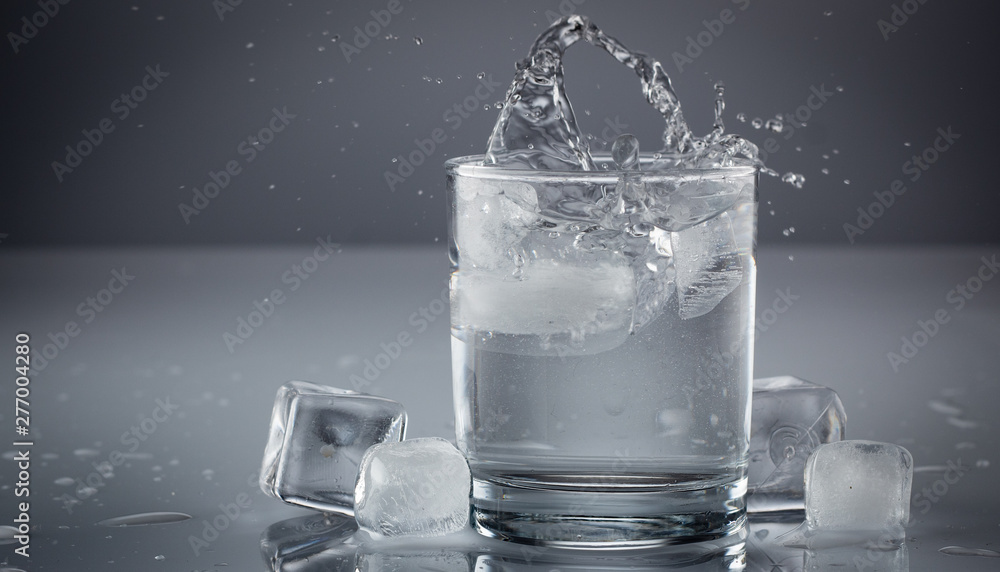 Pouring water into glass on blue background close up Pouring water into glass on blue background close up