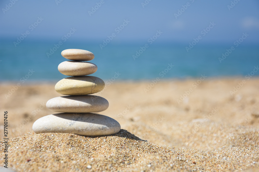 Fototapeta premium Zrównoważona kamienna piramida na piasku na plaży. Zen rock, pojęcie równowagi i harmonii