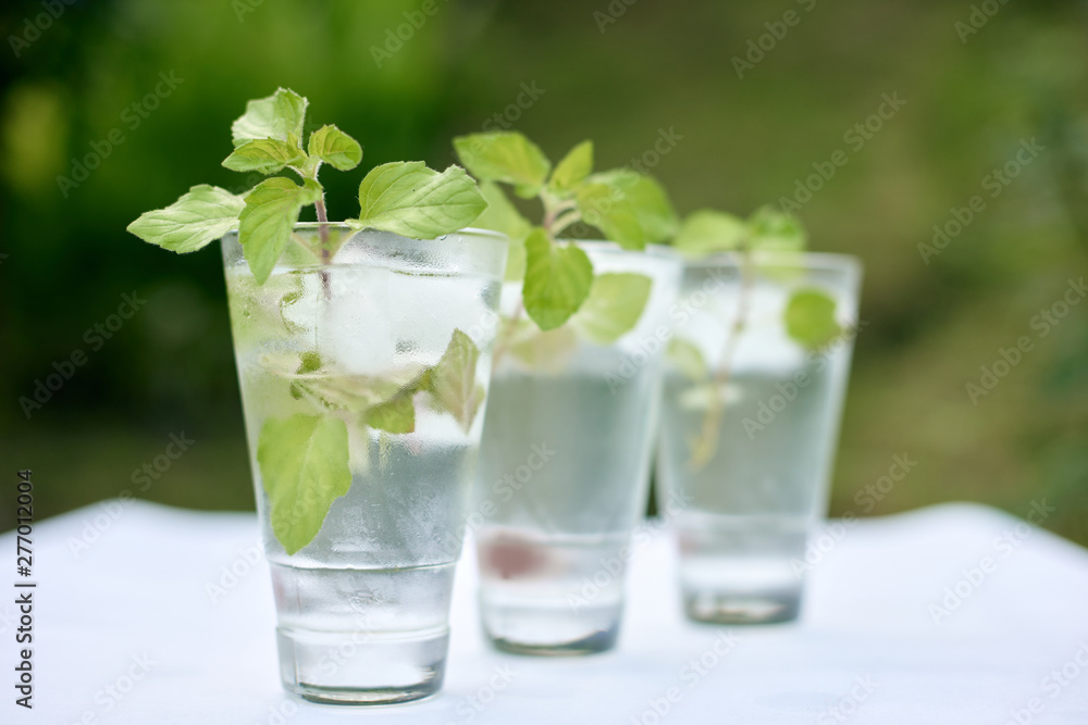 Summer hot fresh drink with mint in glass on white green grey background Summer hot fresh drink with mint in glass on white green grey background