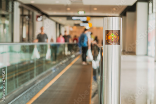 Defocused background of people standing on moving walkway or travelator or autowalk in modern interior building. Selective focus at the pole.