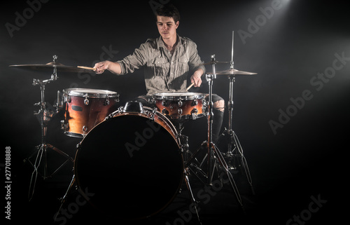 Professional drummer playing on drum set on stage on the black background