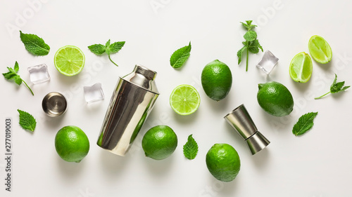 Mojito lime set, flat lay on white background. Concept: Mojito Cocktail. Whole juicy limes with ice and cocktail shaker. Concept: summer refreshing cocktail. © hannamartysheva