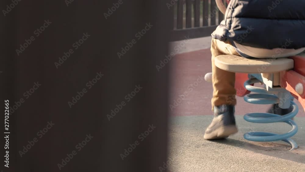 Boy child riding swing horse in public children playground. Pan slow motion Boy child riding swing horse in public children playground. Pan slow motion