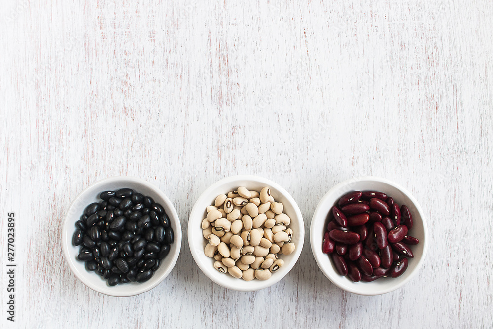 Assortment of beans in white bowl on rustic wood. Assortment of beans in white bowl on rustic wood.