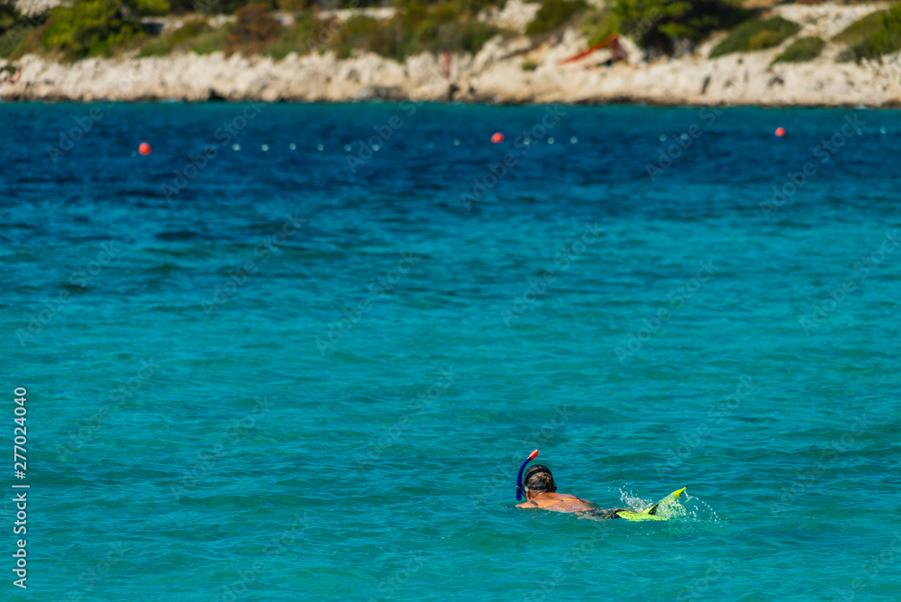 Vacation tourist, young person, snorkeling in paradise clear water. Snorkeler in crystalline waters . Turquoise sea background.