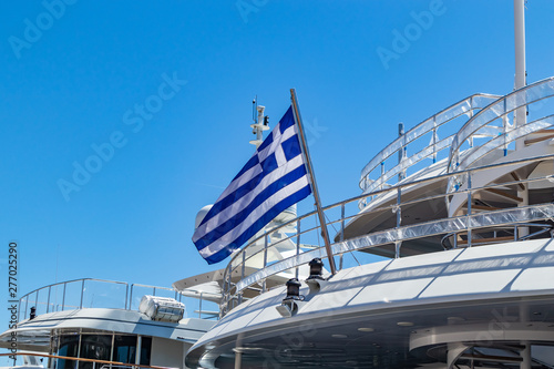 Greek flag on a yacht, cruise to islands. Clear blue sky background