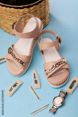 Women's pink summer sandals on a blue background. Women's watches and hairpins.