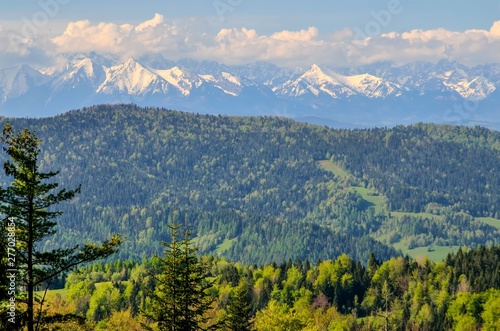 Charming spring mountain landscape. Beautifully snow-covered high peaks over hills.