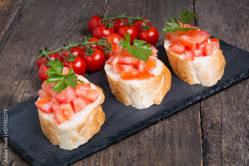 Traditional Italian bruschettas with cherry tomatoes on stone plate