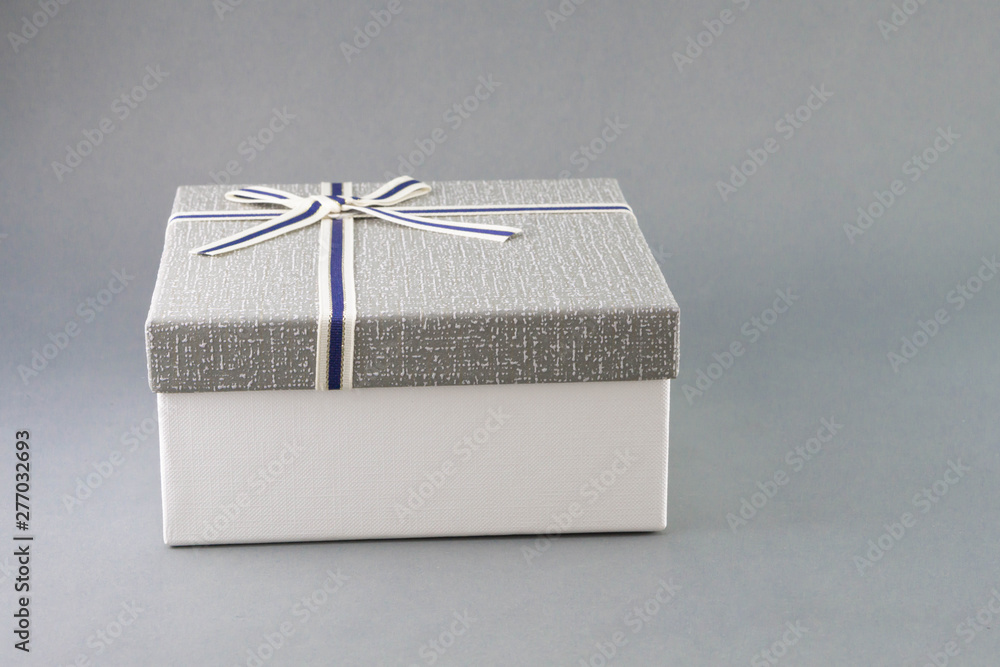 Grey gift box with ribbon on grey background, copy space - obrazy, fototapety, plakaty 