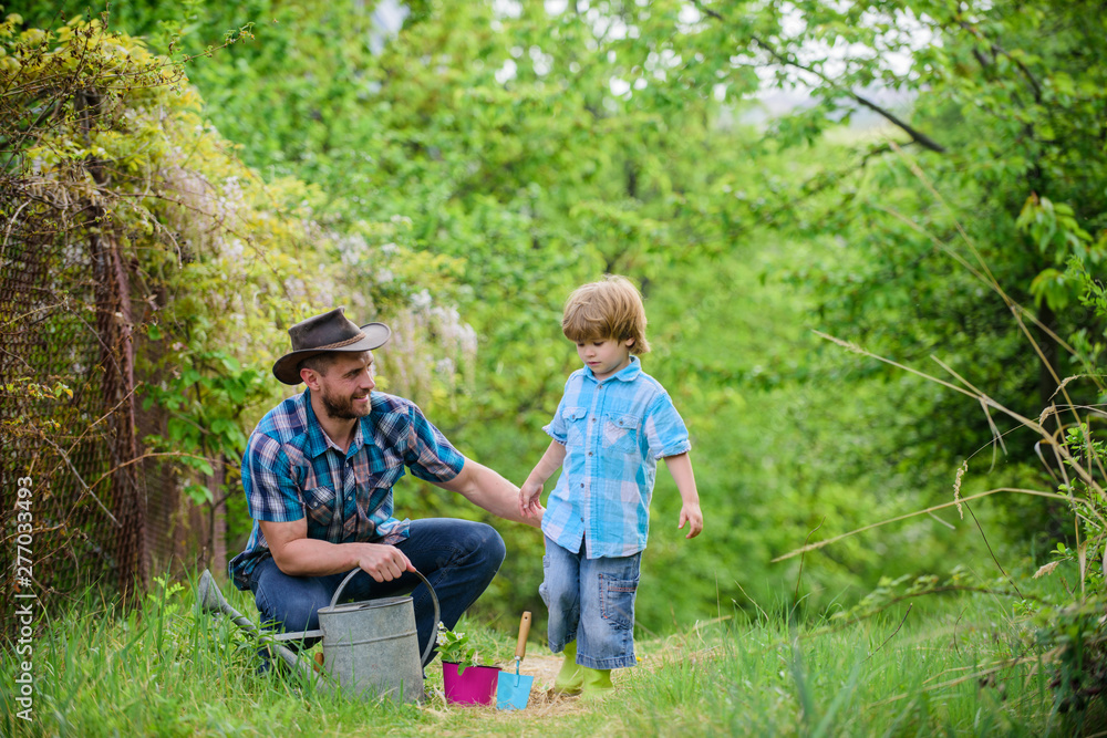 Obraz premium Take care of plants. Boy and father in nature with watering can. Gardening tools. Dad teaching little son care plants. Little helper in garden. Make planet greener. Planting flowers. Growing plants