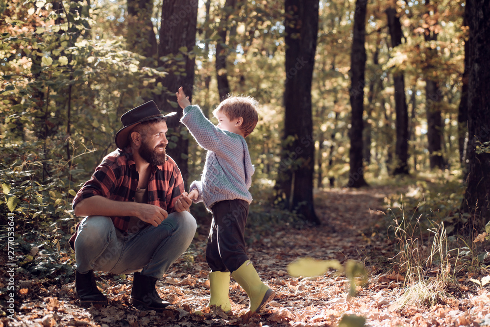 Happy joyful father with a cute son in cowboy hat, family, travel, vacation, father's day - concept. Dad and son in the autumn park play laughing.