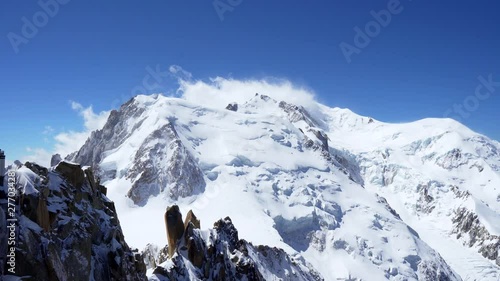 snow covered rocky peaks of the alpine mountains. Mont Blanc mountain in a cloud against a blue sky