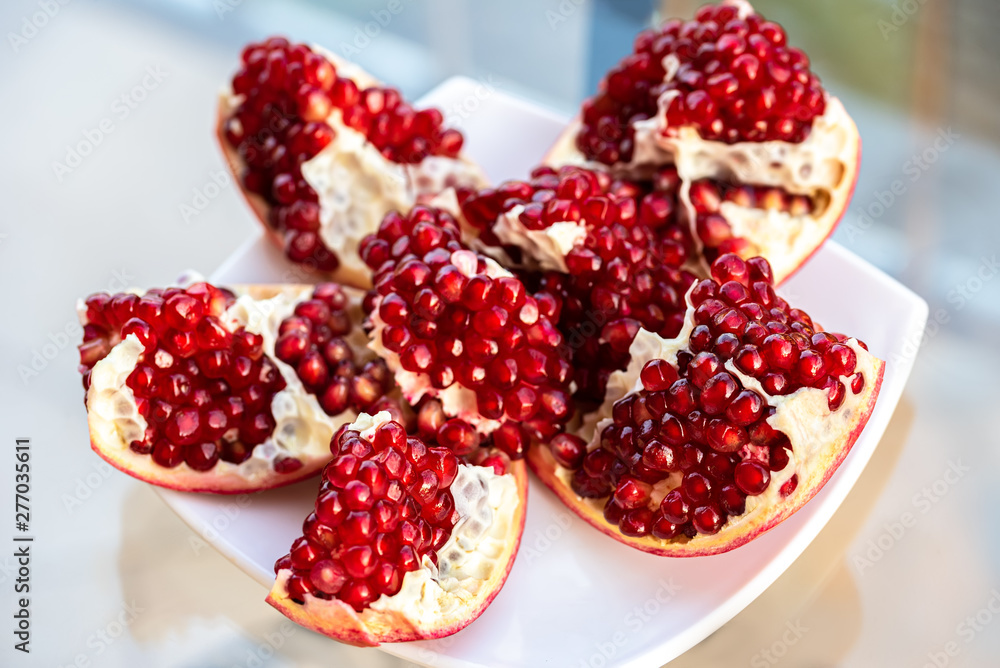 The fresh red tasty opened pomegranate on a white dish The fresh red tasty opened pomegranate on a white dish