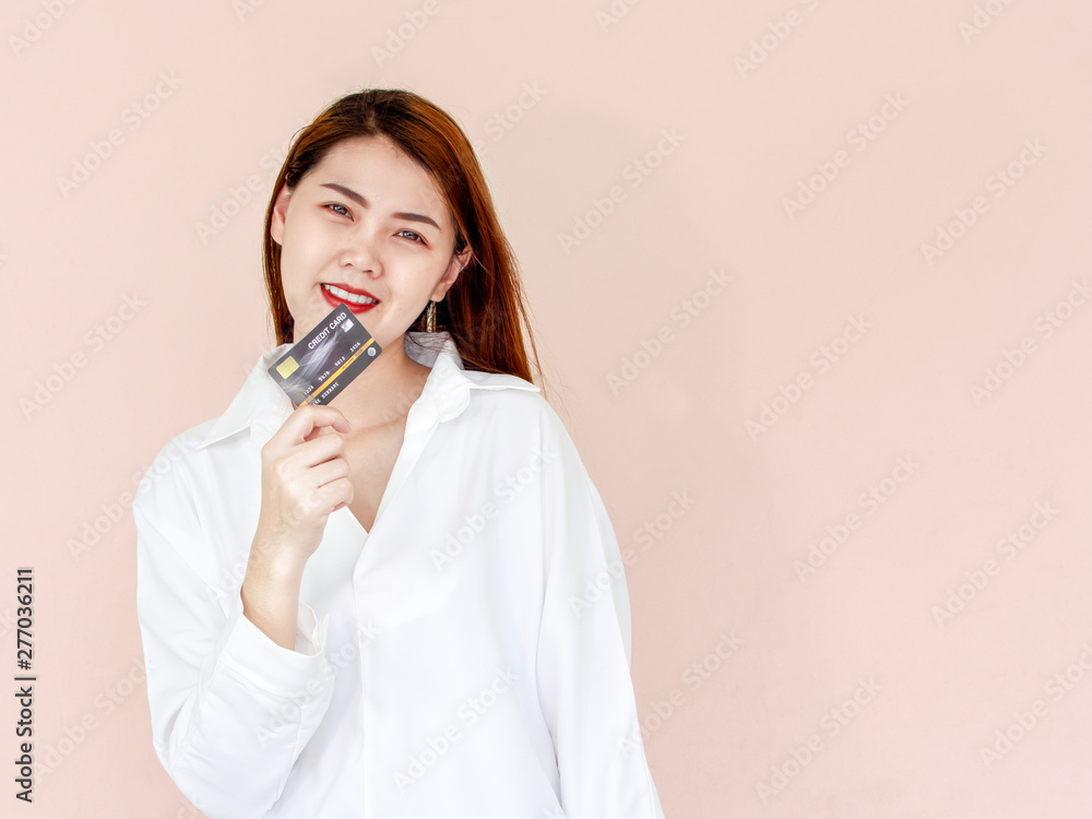 Happy young asian woman holding credit card in hand, showing confidence for making payment with feeling excited and amazed, isolated on pink background. Happy young asian woman holding credit card in hand, showing confidence for making payment with feeling excited and amazed, isolated on pink background.