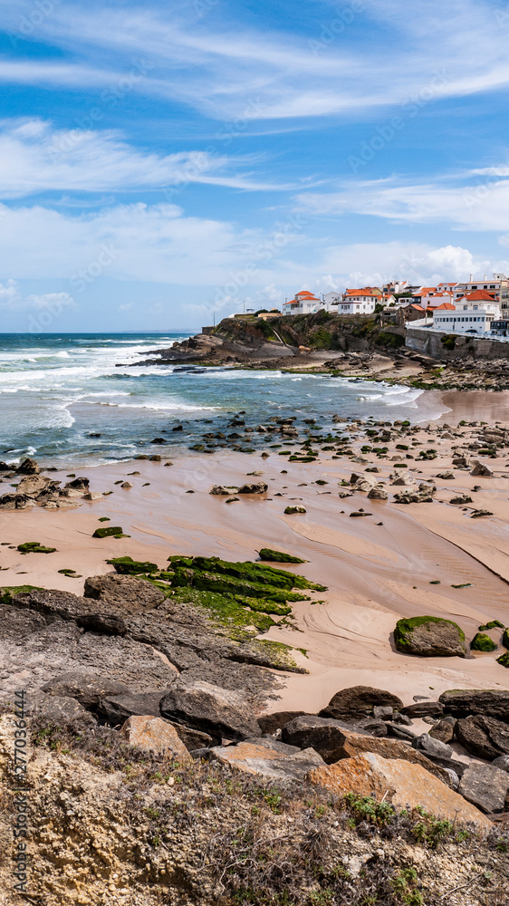 Praia das Maçãs, Portugal on a sunny summer day - a beautiful view of the beach & village, large waves and a blue sky.