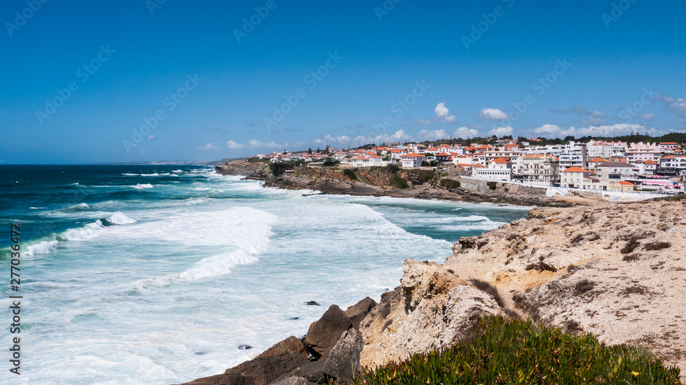 Praia das Maçãs, Portugal on a sunny summer day - a beautiful view of the beach & village, large waves and a blue sky.