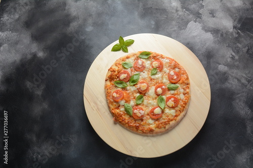Homemade Italian Neapolitan pizza Margherita with melted mozzarella cheese and tomatoes garnished with fresh basil