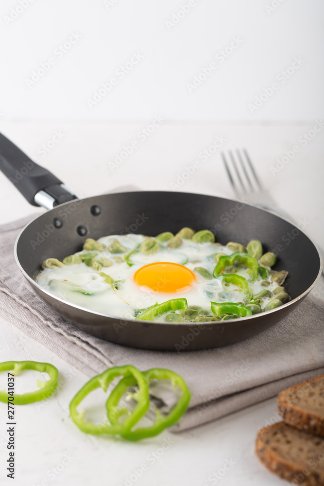 Green shakshuka. Fried eggs with fresh pepper, beans on a gray background, rustic style Green shakshuka. Fried eggs with fresh pepper, beans on a gray background, rustic style