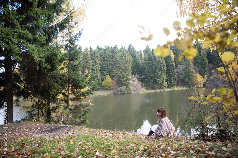 A beautiful brunette girl with curls, autumn in the Park by the water reading a book, clothes beige wool large knit, scarf warm, wind blowing, yellow foliage. A beautiful brunette girl with curls, autumn in the Park by the water reading a book, clothes beige wool large knit, scarf warm, wind blowing, yellow foliage.